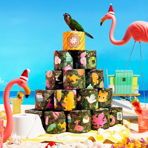 A stack of Stack A Tree Edition rolls on the beach with festive tropical birds on a beach somewhere in the Southern Hemisphere.
