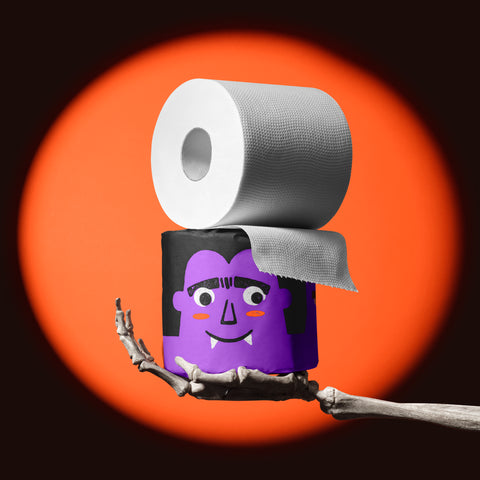 Skeleton hand holding a purple vampire roll of Spooky Edition bamboo toilet paper, unravelling in an orange spotlight