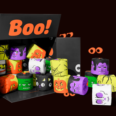 Open black box packed with Halloween-printed bamboo toilet paper rolls in orange, purple, green and white. Box reads "Boo!" on the inside of the box.